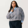 Woman wearing blue and grey plus-size sweater. Must-have all swearters.