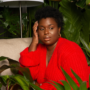 plus size woman wearing a red sweater dress sitting in a garden.